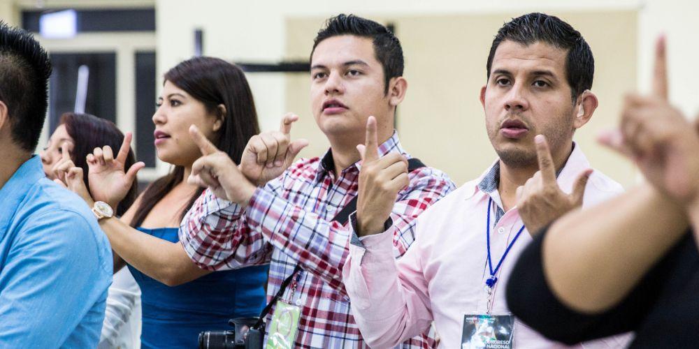 Participantes cantam na linguagem de sinais durante conferência